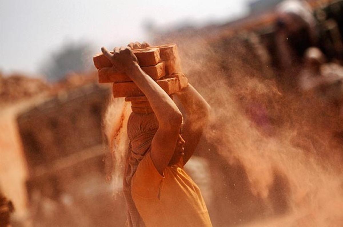 Un obrer nepalès carrega sis totxos en una fàbrica dels afores de Kàtmandu (Nepal).