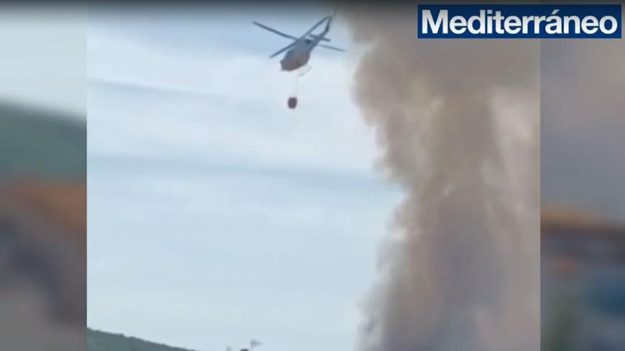 Un helicóptero recoge agua para extinguir las llamas en Cortes de Arenoso