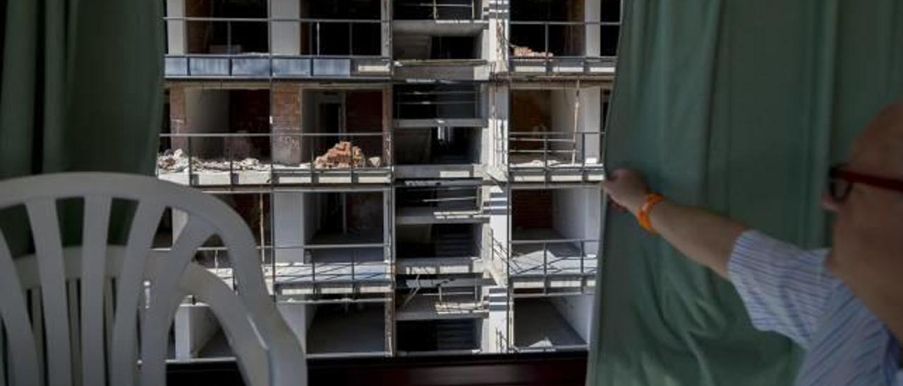 Un vecino muestra los restos de obra que se pueden ver desde los balcones del edificio. A la derecha, elementos de obra en la piscina.