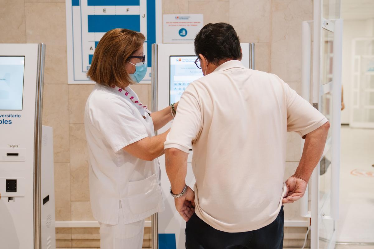 Una celadora informa a un paciente en el Hospital de Móstoles.