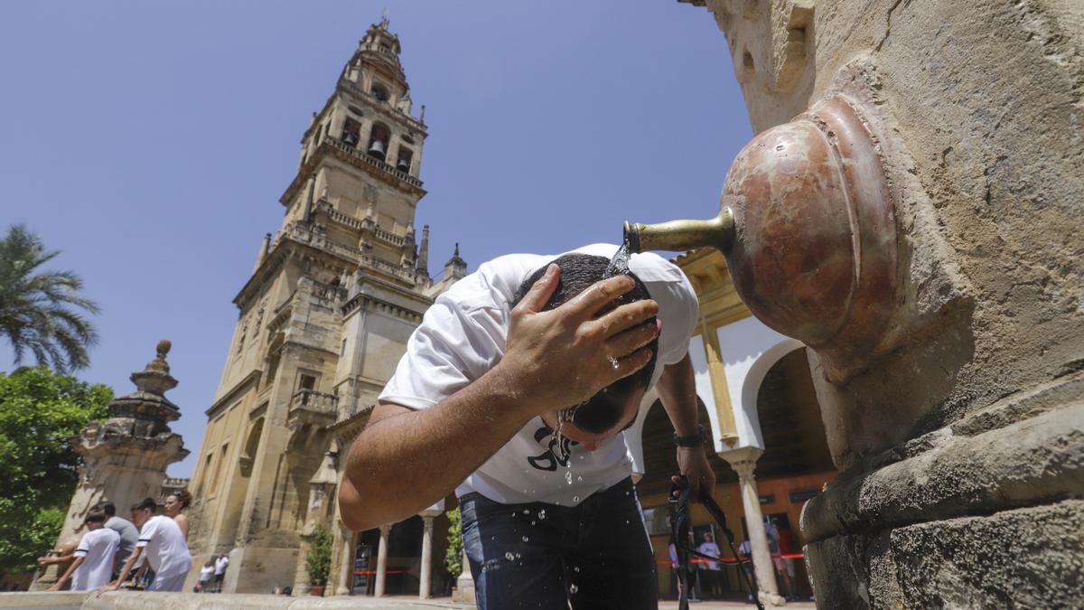 Un turista se refresca la cabeza en el Patio de los Naranjos de la Mezquita Catedral.