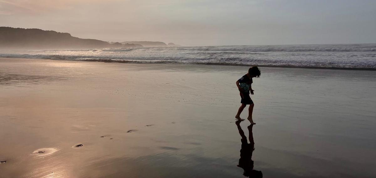 Un niño jugando en el arenal entre Salinas y San Juan al atardecer.