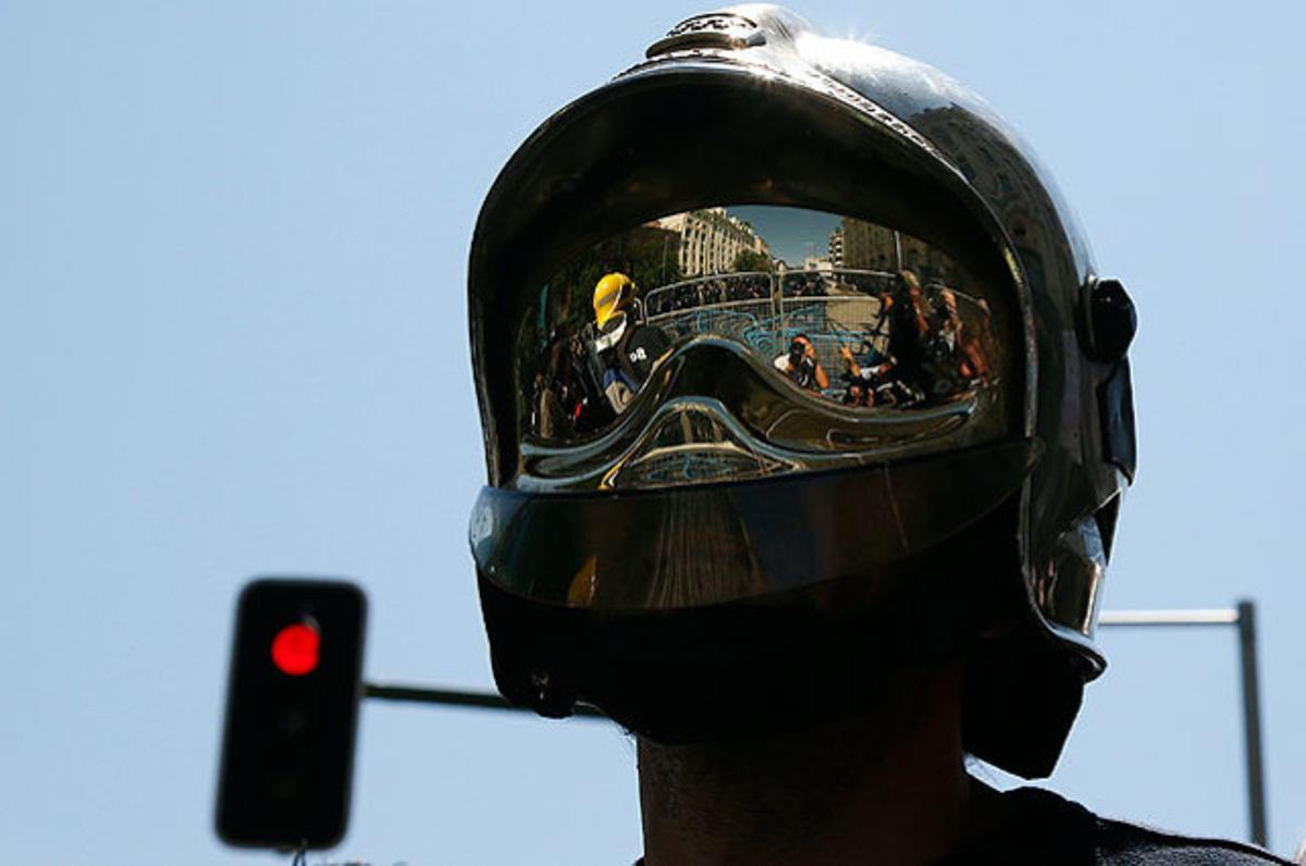 Fotògrafs i policia es reflecteixen en el casc d’un bomber durant una protesta de funcionaris per les últimes retallades del Govern en el centre de Madrid.