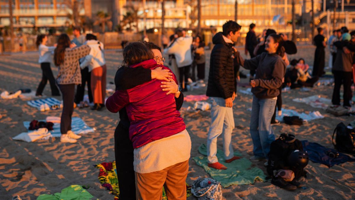 Diversas personas se abrazan en la playa.