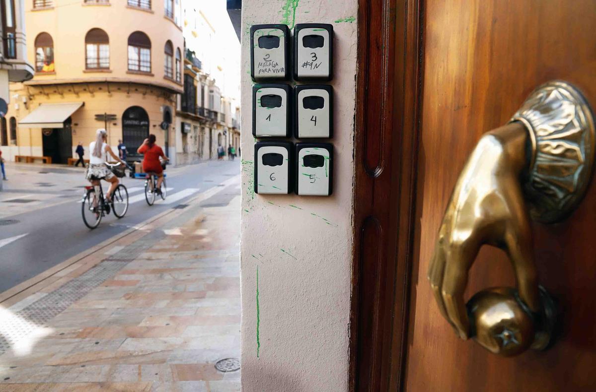 Varios turistas pasan cerca de cajas o cajetillas de llaves de los pisos turísticos que hay en el casco histórico de Málaga.