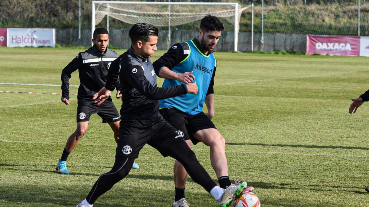 Dani Hernández y Juanan pugnan un balón en un entrenamiento ante la mirada de Yanis. | ZCF