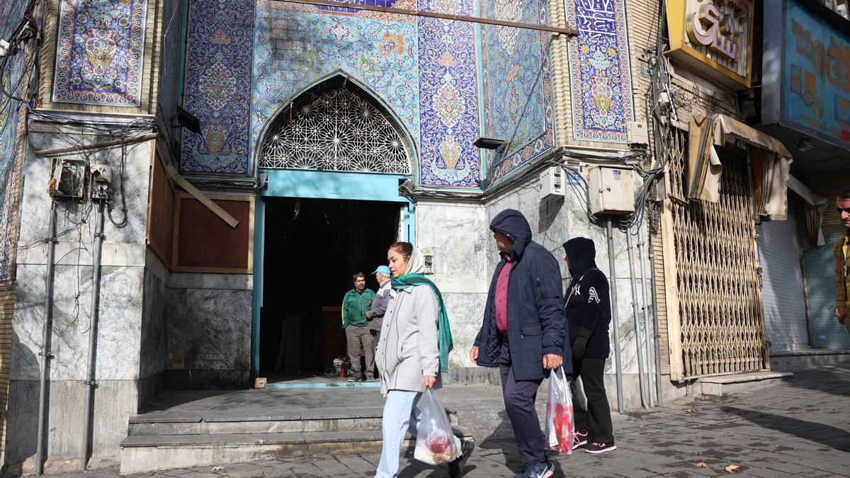 Una pareja pasa frente a una mezquita incendiada durante la reciente ola de protestas en Teherán, este miércoles.