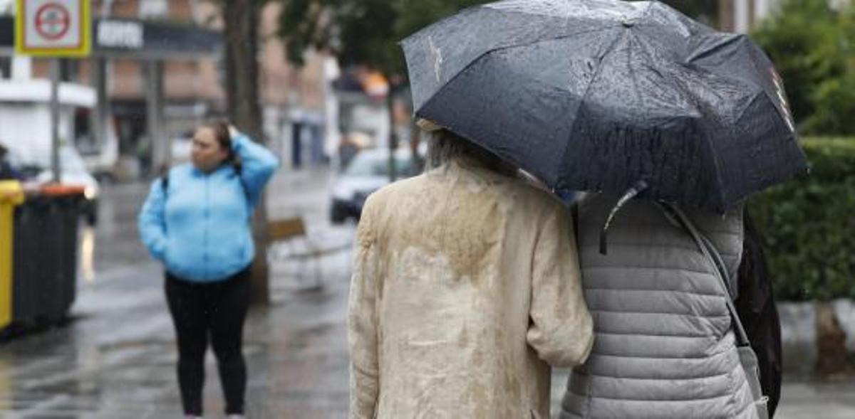 Una pareja se protege con un paraguas de la lluvia