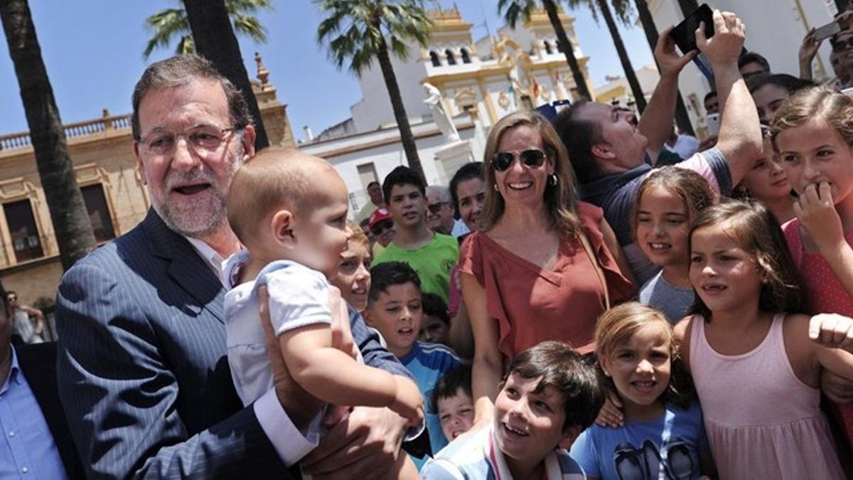 El presidente del Gobierno, Mariano Rajoy, rodeado de niños, en La Palma del Condado (Huelva), este martes, 4 de agosto.