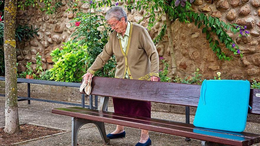 Una dona gran desinfecta un banc abans d&#039;asseure-s&#039;hi.