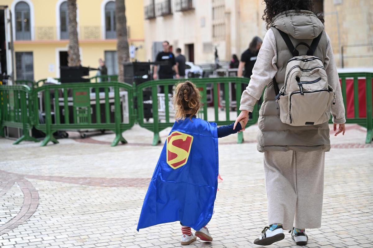 Una madre con su hija vestida de superheroína mientras los técnicos recogen el escenario