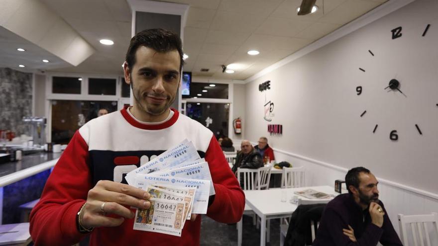 Rubén Alonso, ayer, posando con sus números premiados del sorteo del Niño en su cafetería Dami, en Gijón.