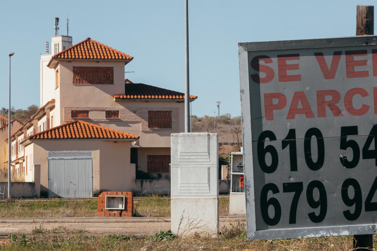 Un chalé tapiada al fondo con un cartel de 'Se Vende' terrenop en Alcaudete de la Jara.