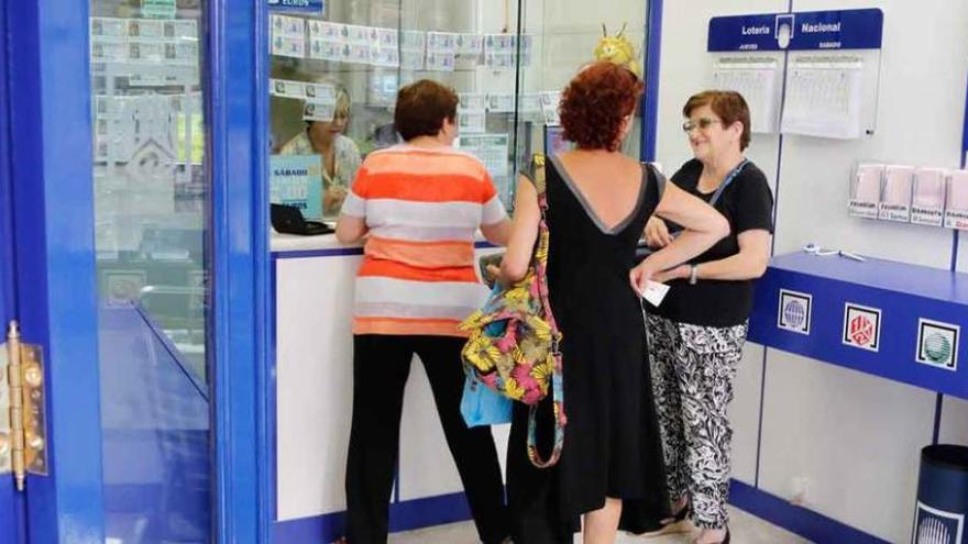 Tres personas hacen cola en una administración de lotería.