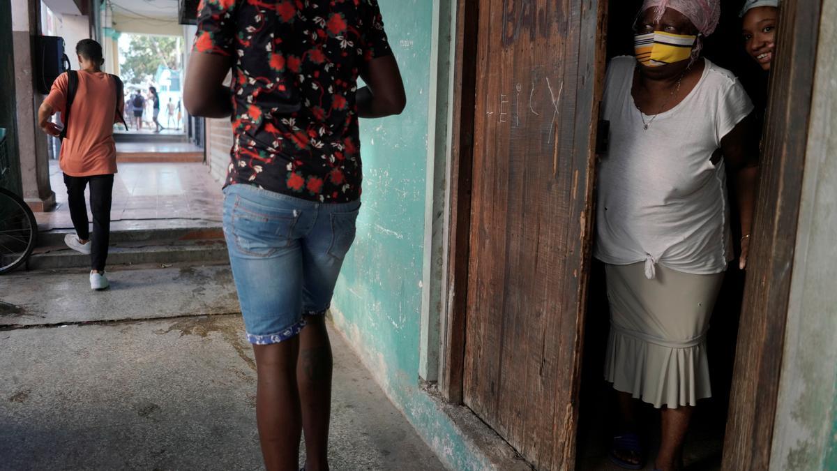 Una mujer mira desde la puerta en La Habana.