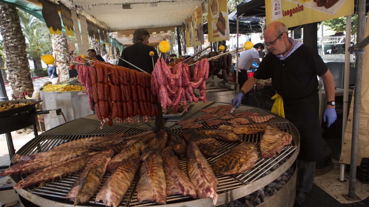 Empleados de una barraca preparan platos de carne