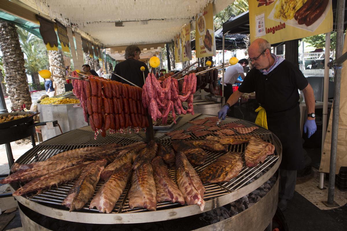 Empleados de una barraca preparan platos de carne