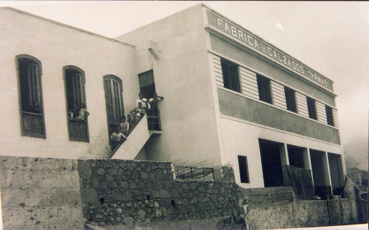 Vista de la zona exterior de la trasera de la Fábrica, en una foto de la familia Armas, con personas en las escaleras de acceso y los ventanales.