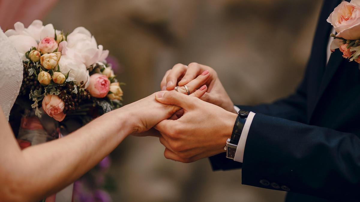 Un novio pone el anillo de boda a su esposa.