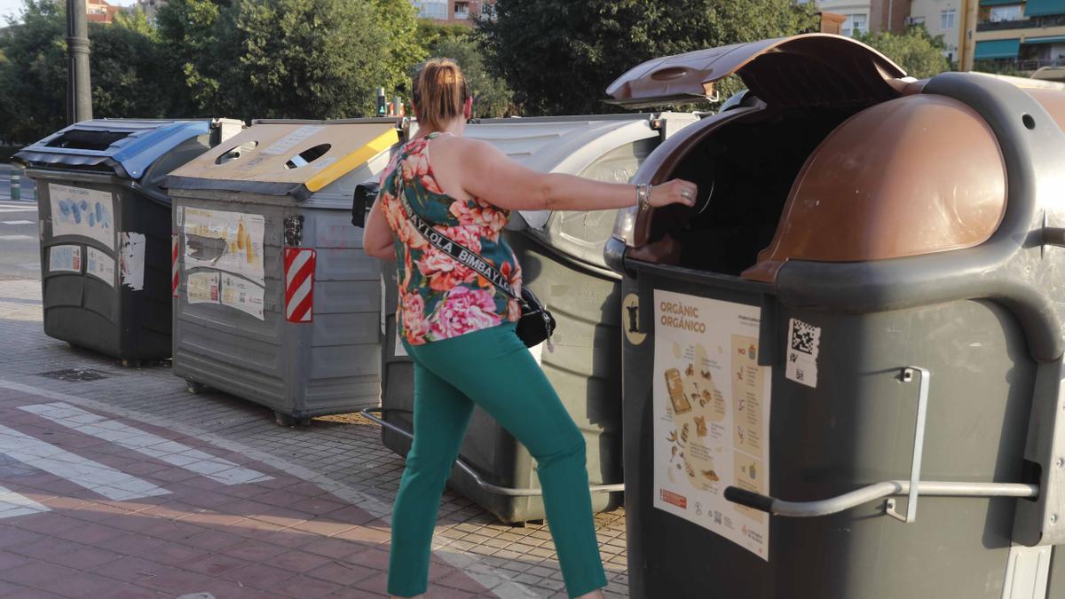 Una dona tirant les deixalles a un contenidor a València.