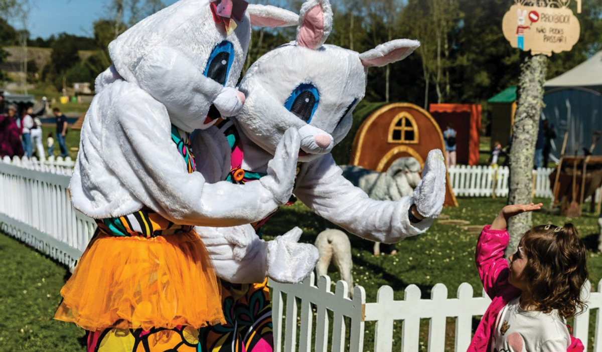 Una niña saluda a dos figurantes vestidos de conejo en este mercado de Pascua gratuito.