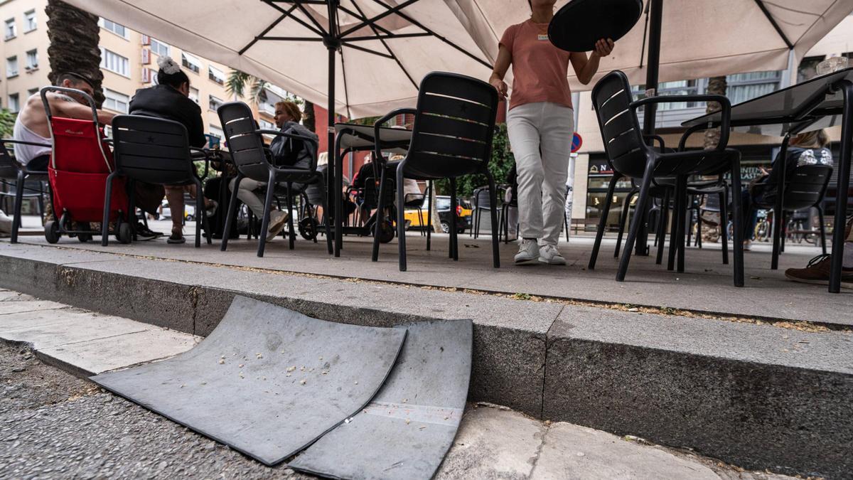 Unas alfombrillas cubren una tapa de alcantarilla frente a una terraza en la Rambla del Poblenou, en Barcelona.