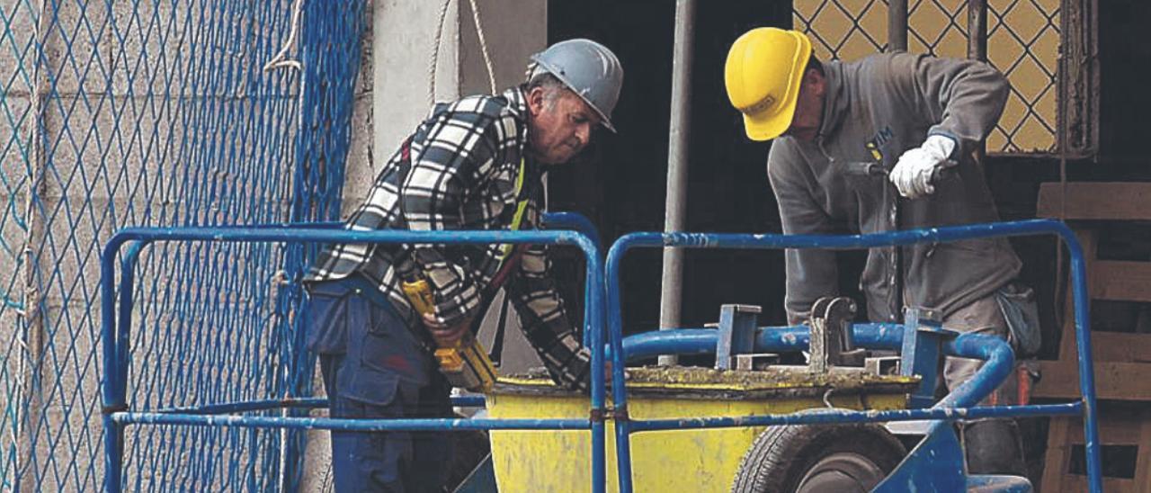 Dos obreros trabajan en la fachada de un edificio. | | ANDRÉS CRUZ