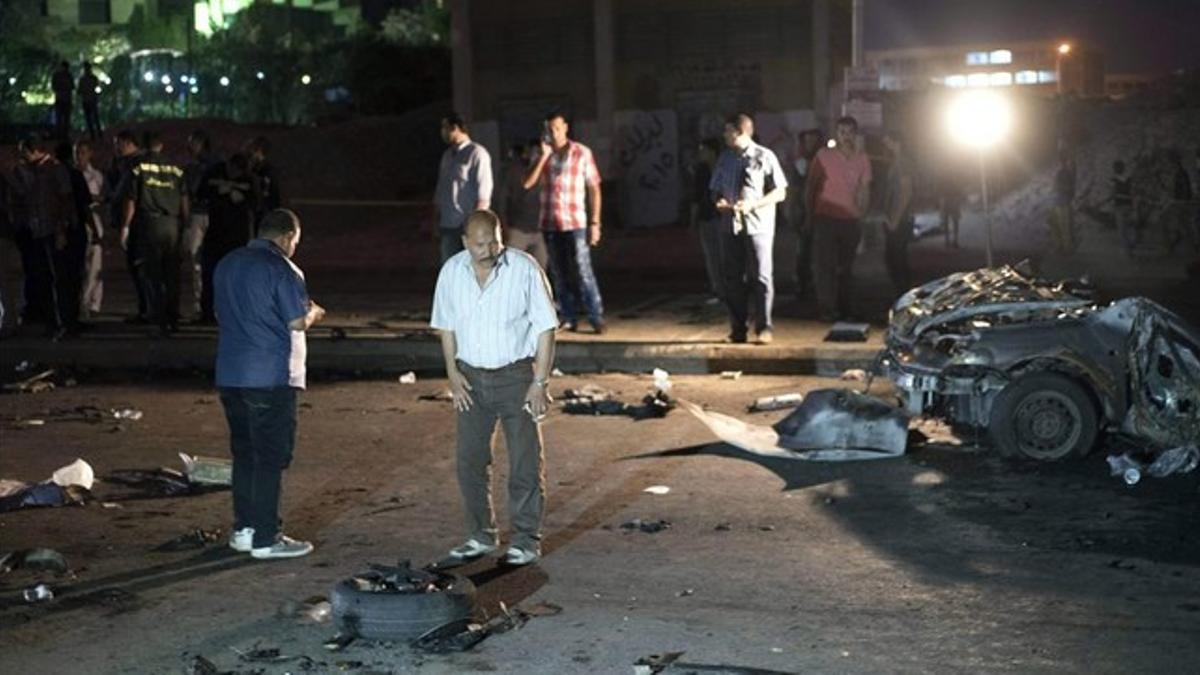 Oficiales de seguridad inspeccionan los restos de un coche bomba que estalló este martes en un distrito de Guiza, vecina de El Cairo.