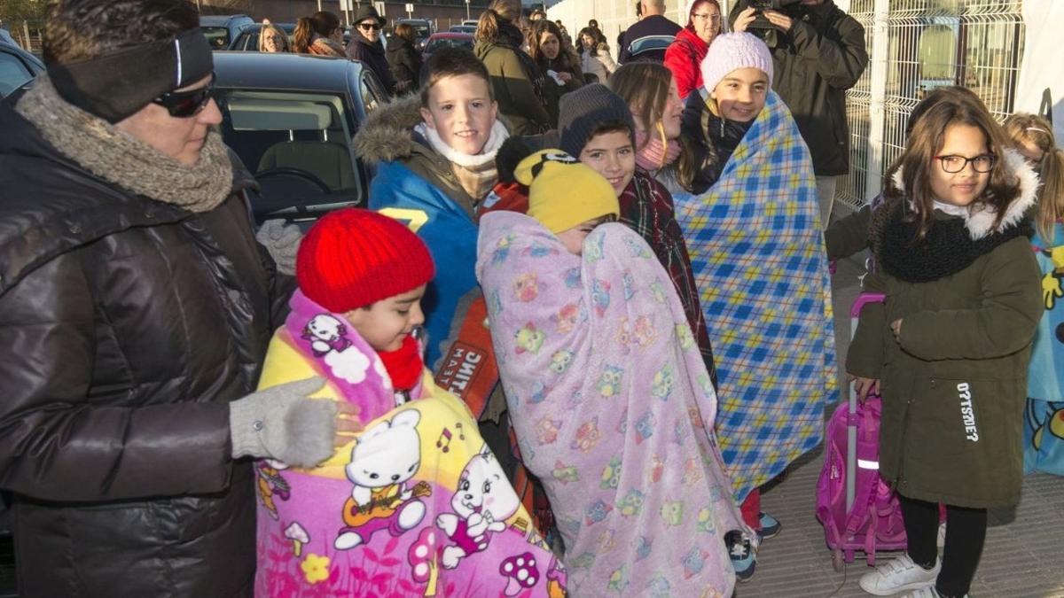 Niños protegidos con mantas a la entrada de la escuela.