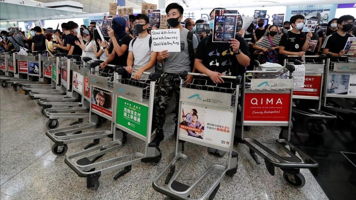 Manifestantes usan carritos para hacer barricadas frente a las puertas de acceso en el aeropuerto de Hong Kong