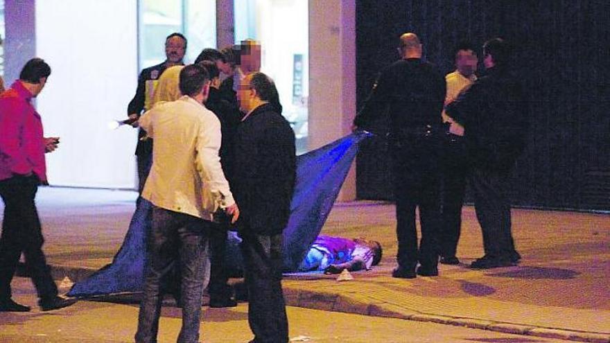 Agentes de la Policía Nacional levantan la lona que cubre el cuerpo de Roberto Lazcano.