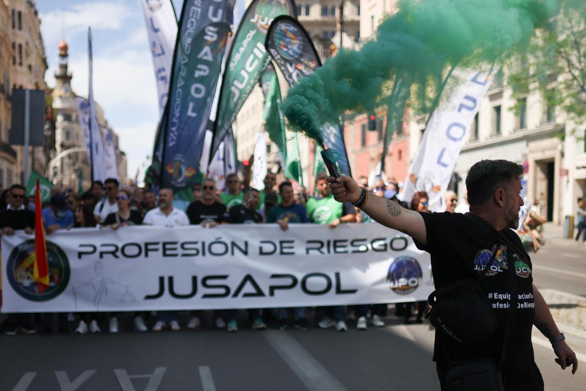 Decenas de personas sostienen una pancarta con lema 'Profesión de riesgo JUSAPOL' durante una manifestación convocada por los sindicatos JUSAPOL, JUPOL y JUCIL, a 18 de abril de 2026, en Madrid (España). La manifestación ha sido organizada en defensa de l