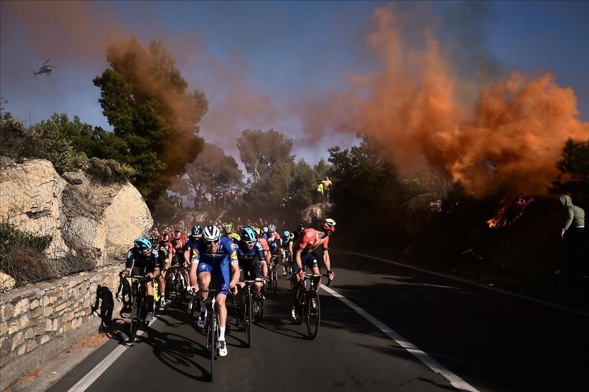 El pelotón de la clásica Milán-San Remo asciende, entre llamas, al puerto de Berta.