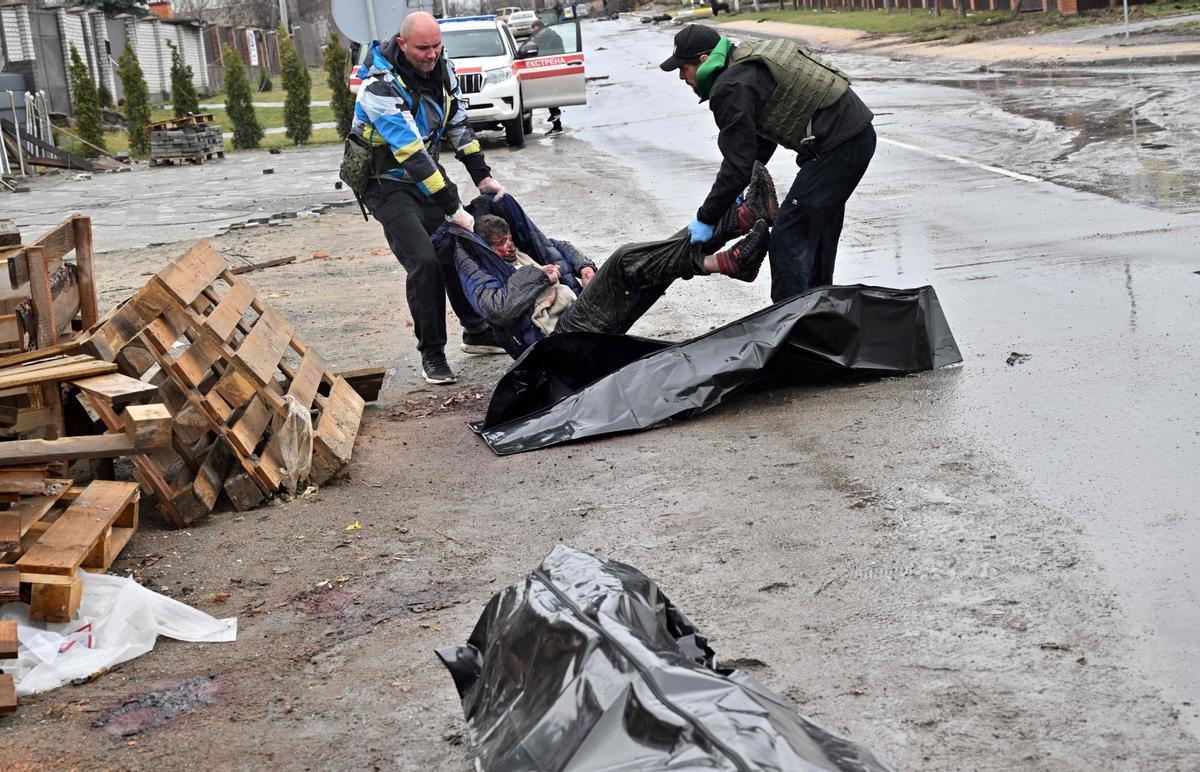 Trabajadores llevan el cuerpo sin vida de un hombre dentro de una bolsa para cadáveres, tras la masacre del ejercito ruso en la localidad de Bucha.