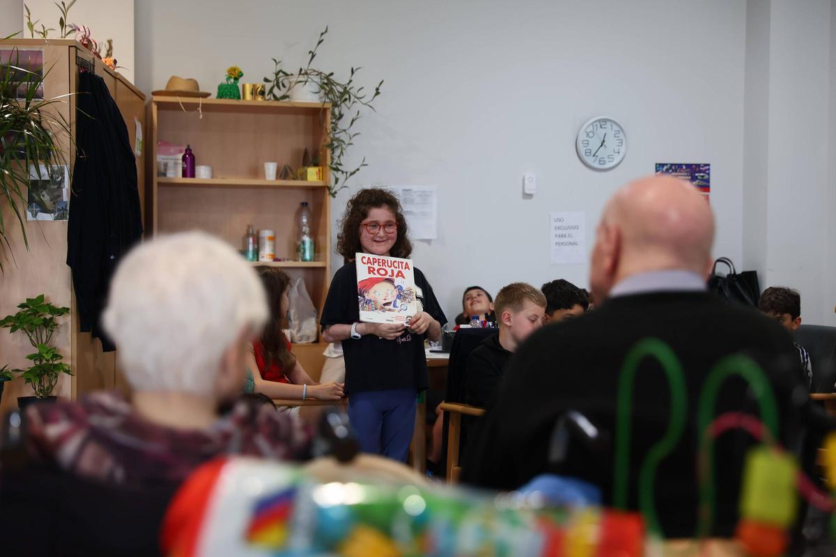 Carmen Albiach enseña su libro a los abuelos.