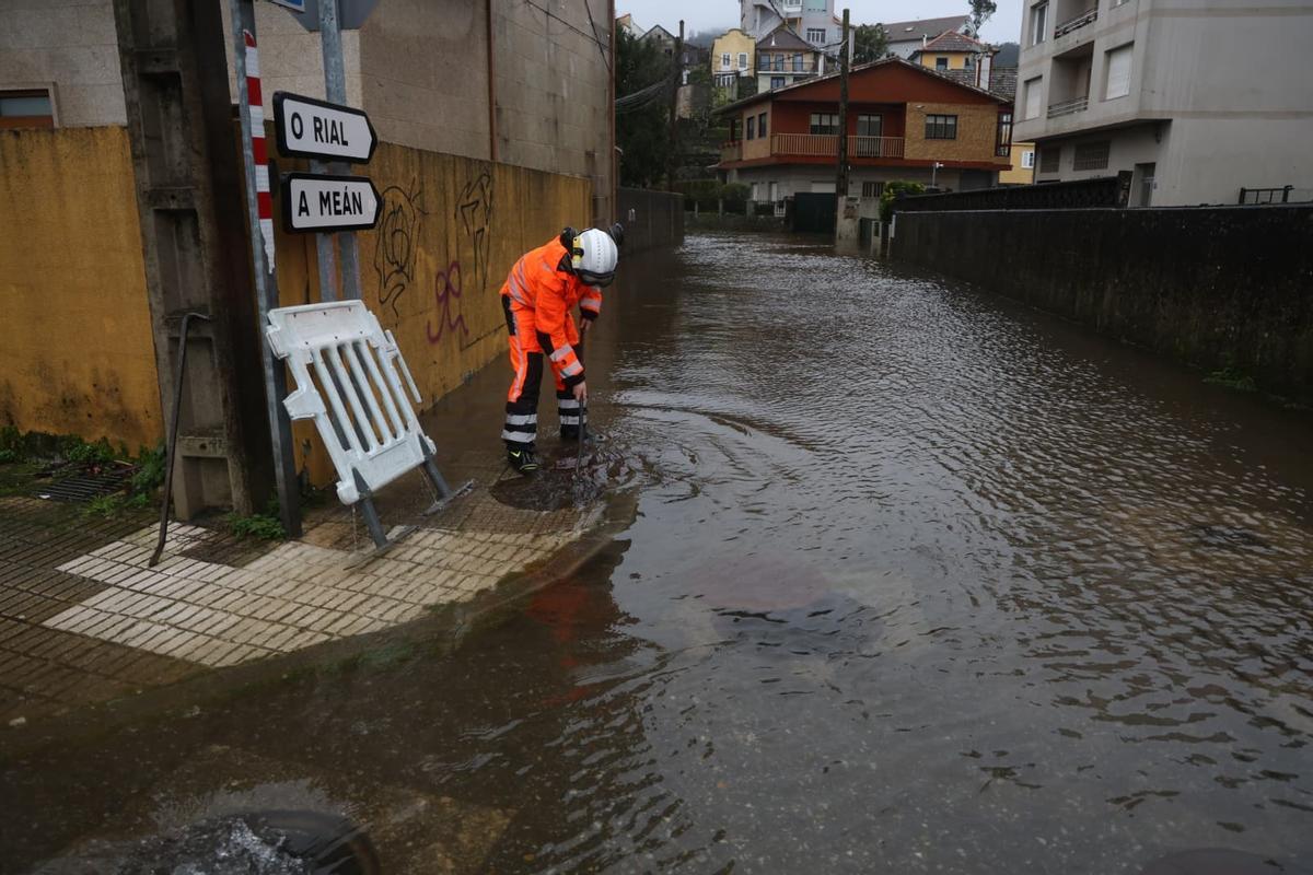 Un efectivo de Proteccion Civil abre las arquetas para aliviar la inundación en la Rúa do Santo