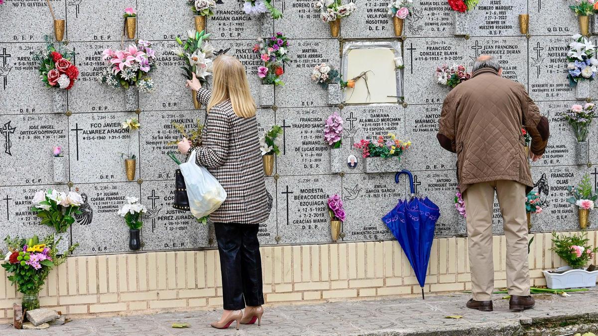Personas limpian y colocan flores como preparativo del Día de Todos los Santos, este domingo en el cementerio de la Almudena en Madrid.