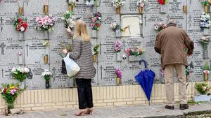 Personas limpian y colocan flores como preparativo del Día de Todos los Santos, este domingo en el cementerio de la Almudena en Madrid.