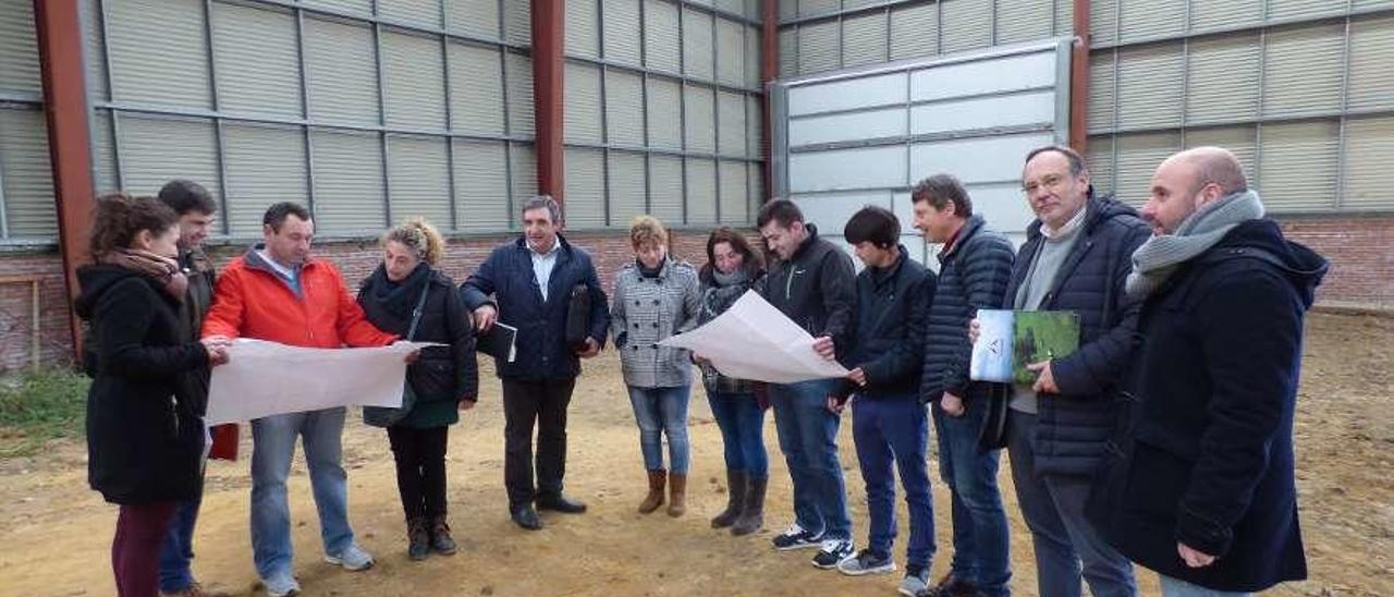 Por la derecha, el concejal Marcos da Rocha, Carlos Manuel Rodríguez y José Ramón Feito observan los planos de la obra junto a los empleados de Mantequera de Tineo y los encargados de la obra, en el interior de la nave del polígono.