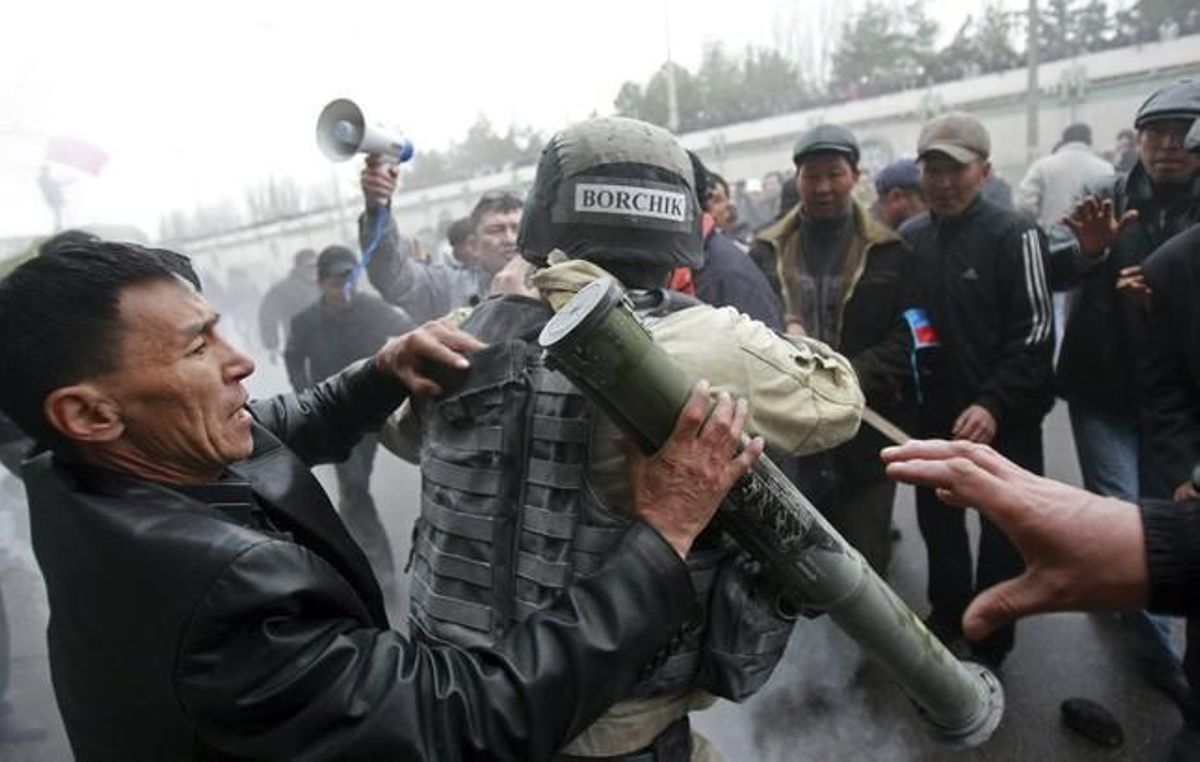 Protesters try to take a rocket propelled grenade from a riot policeman during clashes in Bixkek