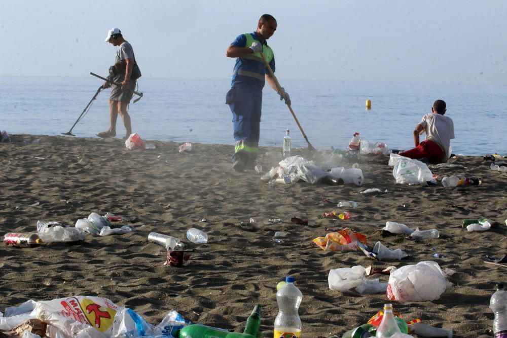 Los operarios de los servicios de limpieza trabajan para dejar la playa en óptimas condiciones tras una larga noche de fiesta en la arena