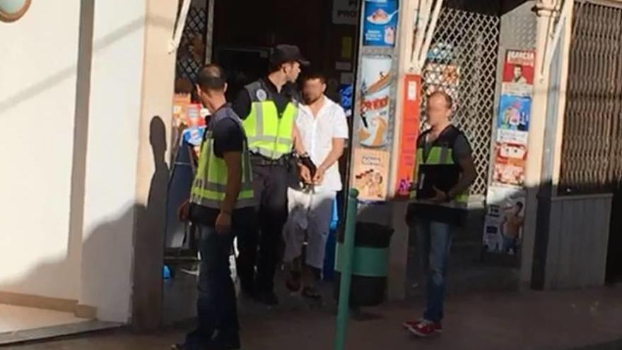 Agentes de la Policía Nacional con el sospechoso arrestado tras inspeccionar un locutorio.