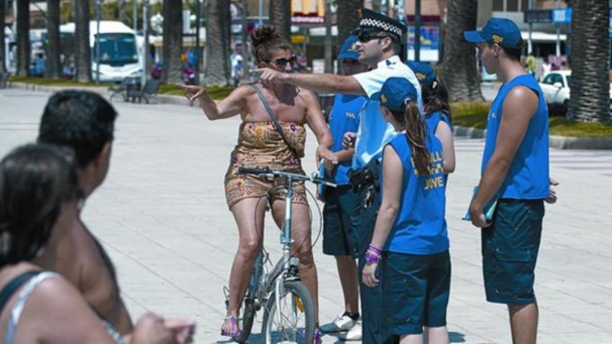 Por allí. Un policía de Salou indica a una ciclista el lugar por donde debe circular, ayer, en presencia de unos voluntarios de la Patrulla Jove.