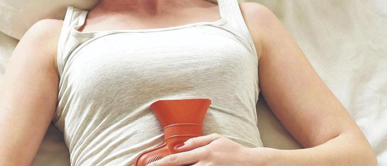 Una mujer con una bolsa de agua caliente para mitigar el dolor menstrual.  | INFORMACIÓN