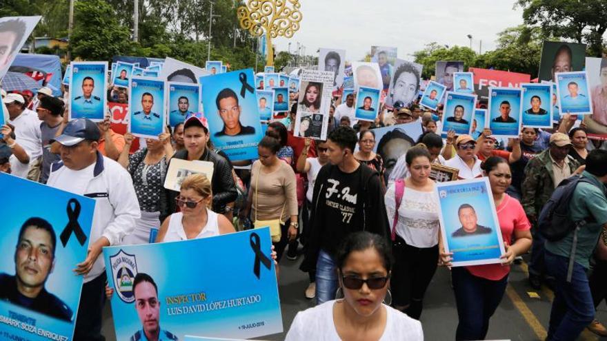 Varios manifestantes muestran fotos de las víctimas.