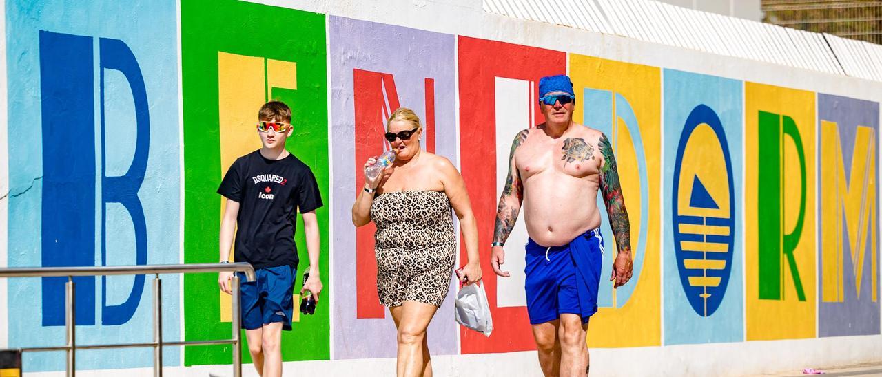 Turistas ingleses con las letras de Benidorm de fondo.