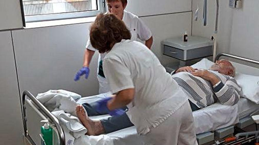 Dues infermeres fan una atenció a un malalt crònic.