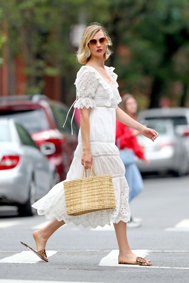 Karlie Kloss con vestido blanco, bolso de rafia y sandalias planas