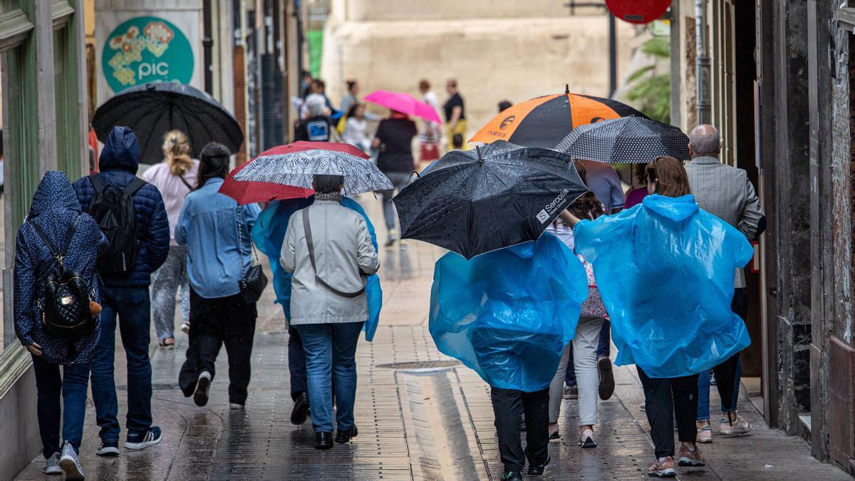 Varias personas pasean con paraguas bajo la lluvia.
