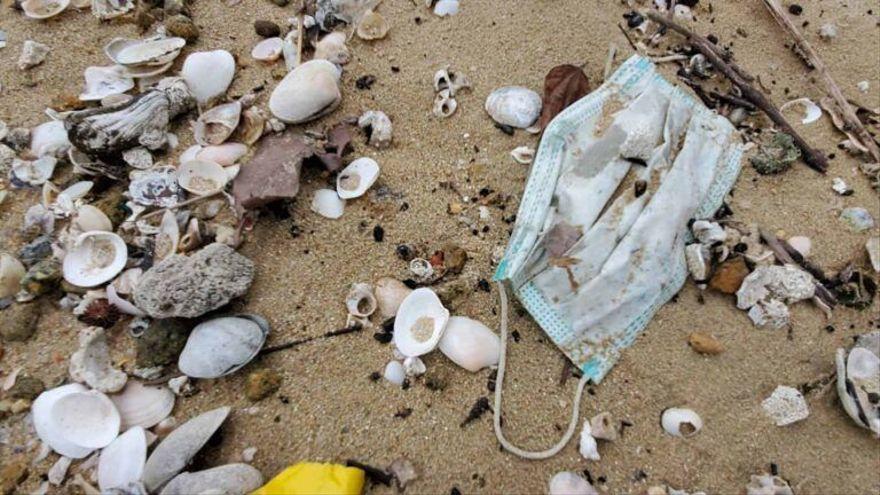 Una mascarilla sanitaria, símbolo de la pandemia de covid-19, aparece tirada en una playa.